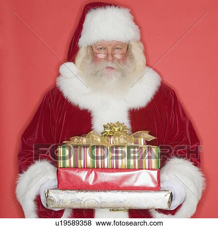 Stock Photo - Santa Claus holding stack of gifts. Fotosearch