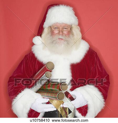 Stock Image - Santa Claus holding wrapping paper and ribbon. Fotosearch