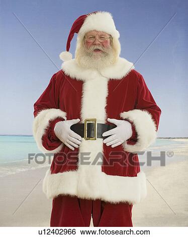 Stock Photograph - Santa Claus laughing at beach. Fotosearch