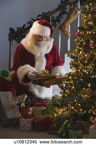 Santa Claus leaving gifts under Christmas tree View Large Photo Image Stock Photography - Santa Claus leaving gifts under Christmas tree. Fotosearch
