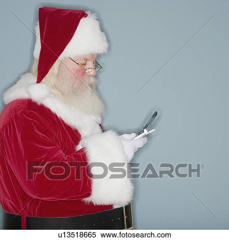 Stock Photography - Santa Claus looking at cell phone. Fotosearch