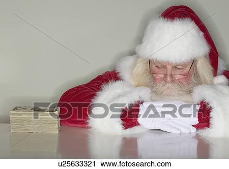 Santa Claus looking at stack of money View Large Photo Image Stock Image - Santa Claus looking at stack of money. Fotosearch