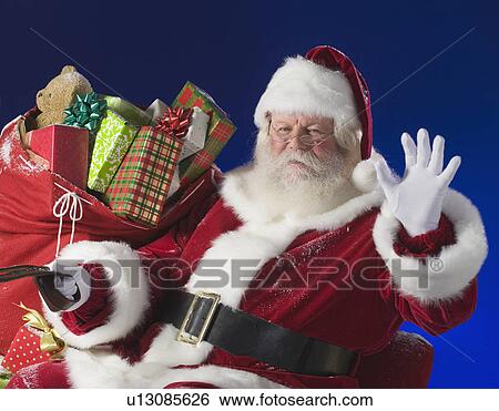 Stock Photograph - Santa Claus next to bag of toys. Fotosearch