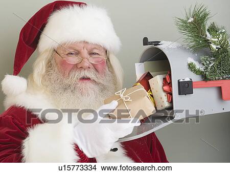 Santa Claus putting gifts in mailbox View Large Photo Image Picture - Santa Claus putting gifts in mailbox. Fotosearch