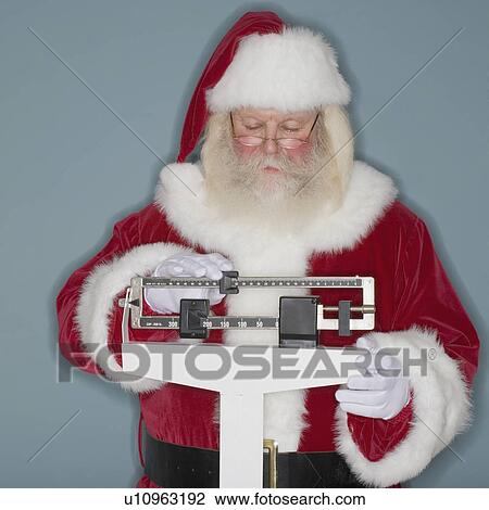 Stock Image - Santa Claus standing on scale. Fotosearch