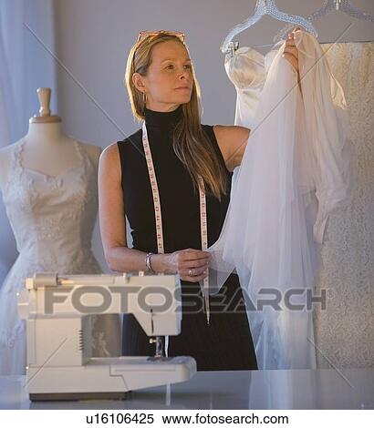 Seamstress looking at wedding dress View Large Photo Image Stock Photography - Seamstress looking at wedding dress. Fotosearch