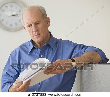 Stock Image - Senior businessman reading paperwork. Fotosearch