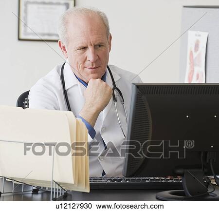 Senior male doctor looking at computer View Large Photo Image Stock Image - Senior male doctor looking at computer. Fotosearch