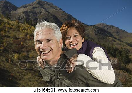 Stock Image - Senior man giving wife piggy back ride, Utah, United States. Fotosearch