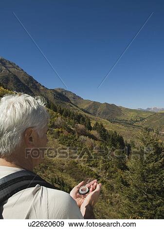 Stock Photo - Senior man holding compass, Utah, United States. Fotosearch