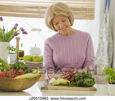 Stock Image - Senior woman looking at vegetables. Fotosearch
