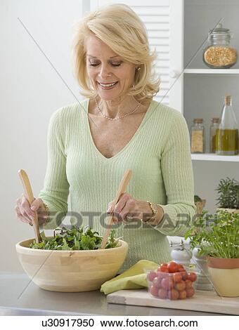 Stock Image - Senior woman tossing salad. Fotosearch