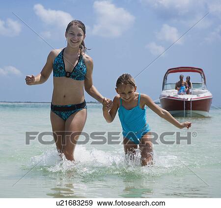 Stock Photo - Sisters running through water, Florida, United States. Fotosearch