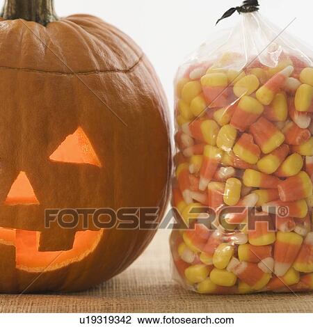 Stock Image - Still life of jack o lantern and candy corn. Fotosearch