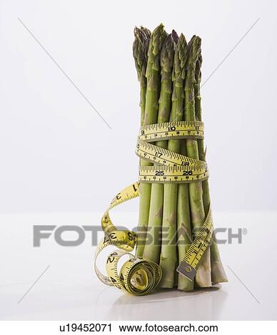 Stock Image - Tape measure wrapped around bunch of asparagus. Fotosearch
