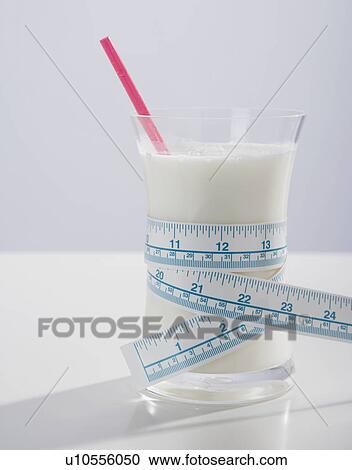 Stock Image - Tape measure wrapped around glass of milk. Fotosearch