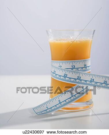 Stock Photo - Tape measure wrapped around glass of orange juice. Fotosearch