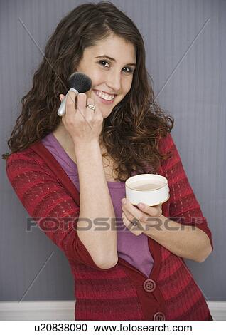 Stock Image - Teenage girl applying face powder. Fotosearch