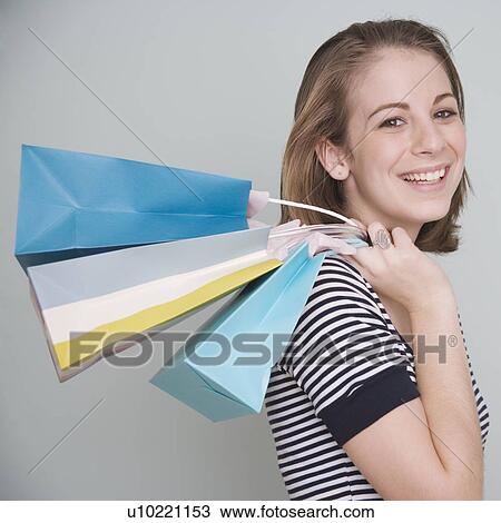Stock Image - Teenage girl holding shopping bags over shoulder. Fotosearch