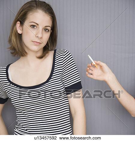 Stock Image - Teenage girl next to friend holding cigarette. Fotosearch