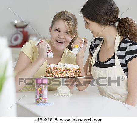 Stock Photography - Teenage girls decorating cake. Fotosearch
