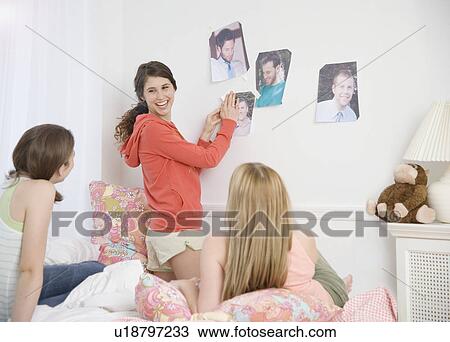 Teenage girls hanging magazine pictures on wall View Large Photo Image Stock Image - Teenage girls hanging magazine pictures on wall. Fotosearch