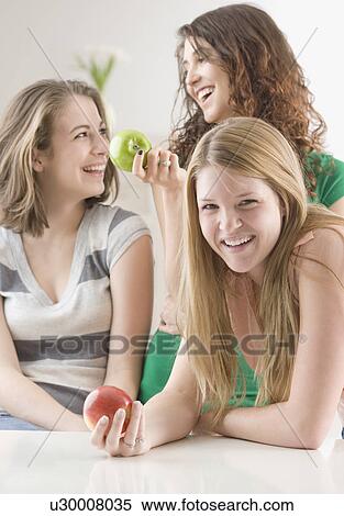 Teenage girls laughing and holding apples View Large Photo Image Stock Photography - Teenage girls laughing and holding apples. Fotosearch
