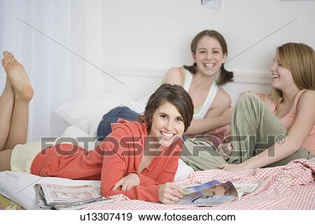 Teenage girls laughing on bed View Large Photo Image Stock Photo - Teenage girls laughing on bed. Fotosearch