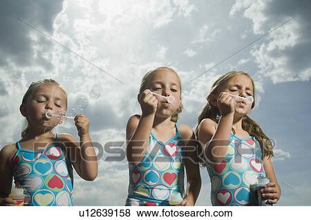 Three young sisters blowing bubbles View Large Photo Image Stock Photo - Three young sisters blowing bubbles. Fotosearch