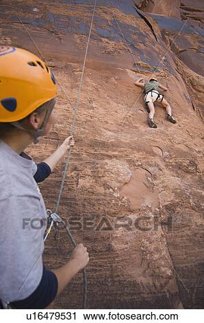 Stock Image - Two people rock climbing. Fotosearch