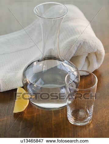 Stock Photo - Water jug and glass next to rolled towel. Fotosearch