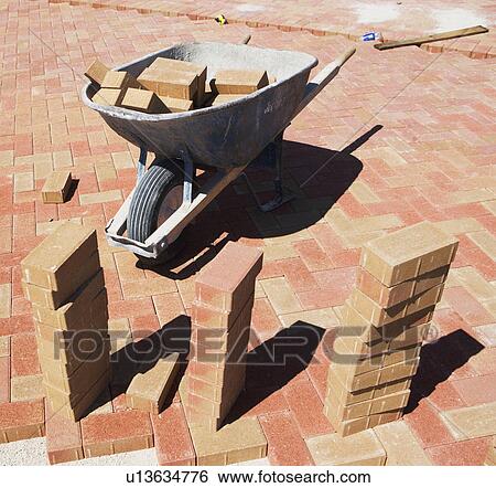 Stock Photograph - Wheelbarrow and bricks on new patio. Fotosearch