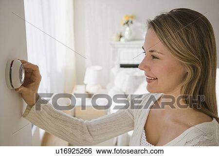 Stock Photograph - Woman adjusting thermostat. Fotosearch
