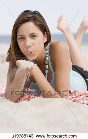 Stock Image - Woman blowing on sand in hands. Fotosearch