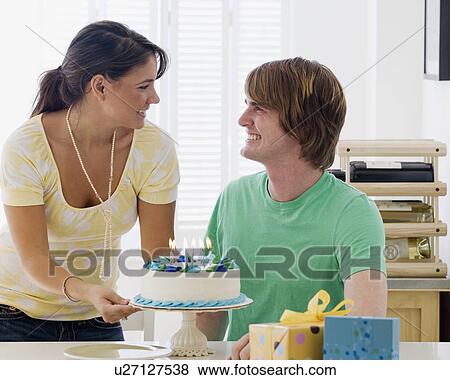 Woman bringing birthday cake to boyfriend View Large Photo Image Stock Photo - Woman bringing birthday cake to boyfriend. Fotosearch