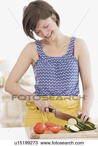 Stock Image - Woman chopping vegetables in kitchen. Fotosearch