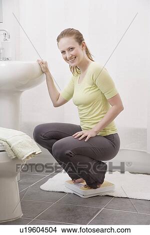 Woman crouching on bathroom scale View Large Photo Image Picture - Woman crouching on bathroom scale. Fotosearch