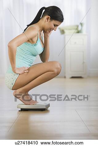 Woman crouching on scale View Large Photo Image Stock Image - Woman crouching on scale. Fotosearch