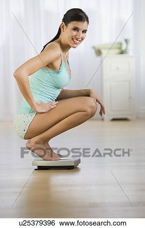 Woman crouching on scale View Large Photo Image Stock Photograph - Woman crouching on scale. Fotosearch