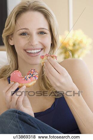 Stock Photo - Woman eating frosted donut. Fotosearch