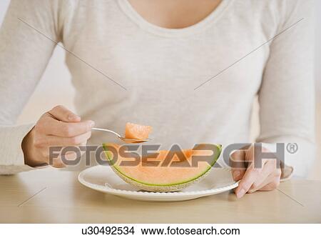 Woman eating melon wedge View Large Photo Image Picture - Woman eating melon wedge. Fotosearch