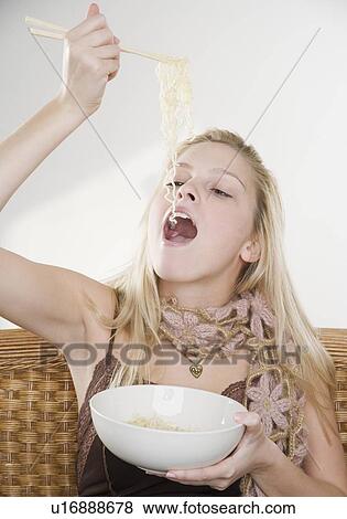 Stock Photo - Woman eating noodles. Fotosearch