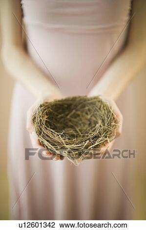 Stock Image - Woman holding bird’s nest. Fotosearch