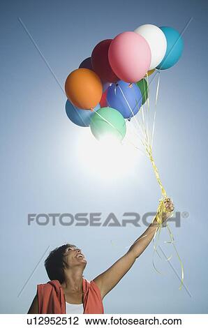 Woman holding bunch of balloons View Large Photo Image Stock Image - Woman holding bunch of balloons. Fotosearch