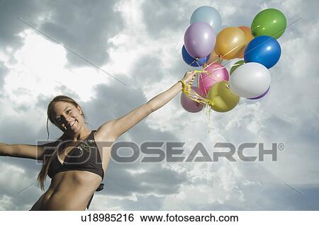 Stock Photograph - Woman holding bunch of balloons. Fotosearch