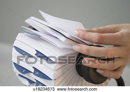 Stock Image - Woman holding card in rotary card file. Fotosearch