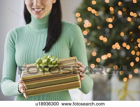 Stock Image - Woman holding Christmas gift. Fotosearch