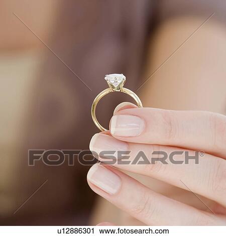 Stock Image - Woman holding engagement ring. Fotosearch