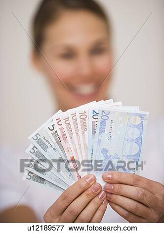 Stock Photo - Woman holding fanned out euro banknotes. Fotosearch