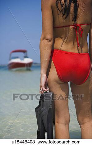 Stock Photo - Woman holding flippers and looking at boat, Florida, United States. Fotosearch